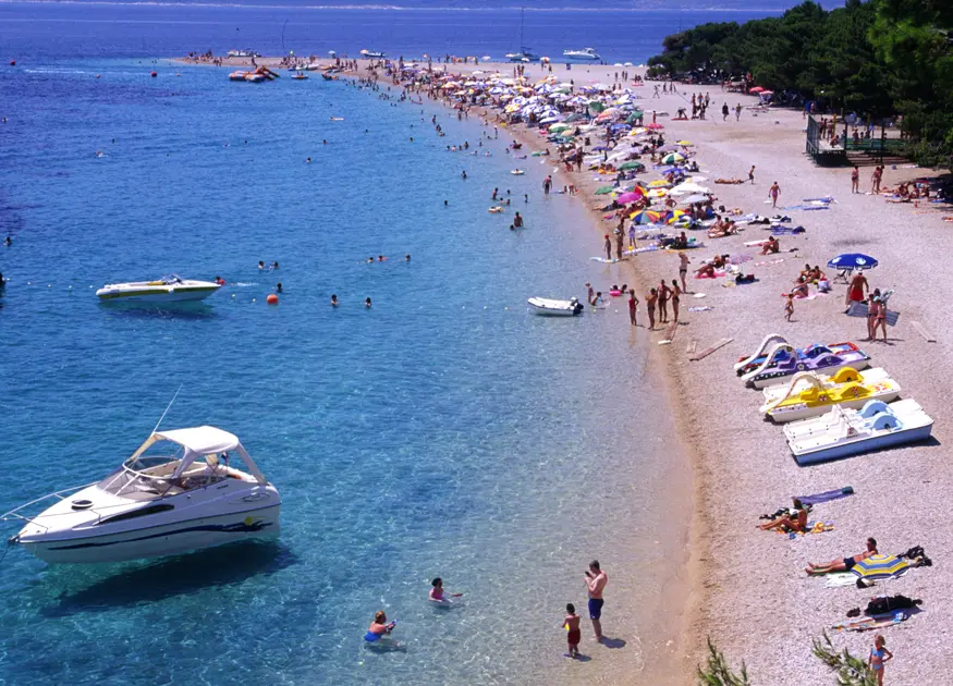 Families on holiday soak up sun and swim in the Dalmatian coast's blue water in the resort town of Bol on the island of Brac (Brach).
