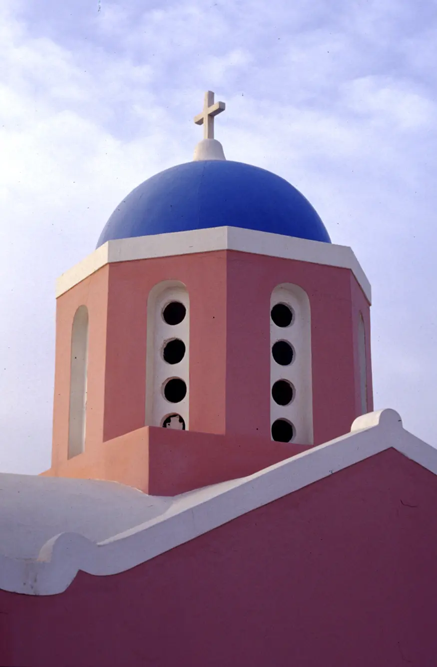 A pink, white, and blue church in Ia, a town in the Greek Cyclades island of Santorini.