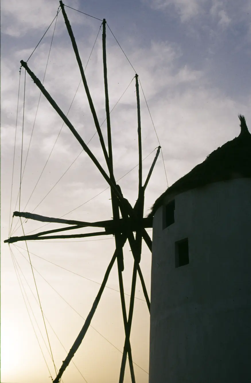 Sun sets behind a windmill on the picturesque town of Ia, located in the Greek Cyclades island of Santorini.