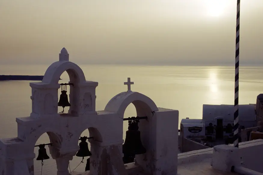 The sun sets beyond a chuch on the picturesque town of Ia, located in the Greek Cyclades island of Santorini.