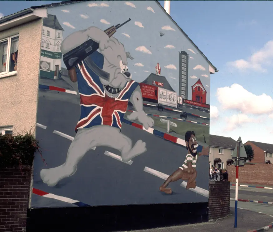 Cartoon mural in Protestant Shankill Road area of Belfast depicting a caricature of Sinn Fein leader, Gerry Adams, being chased back to Dublin by a Loyalist bulldog.