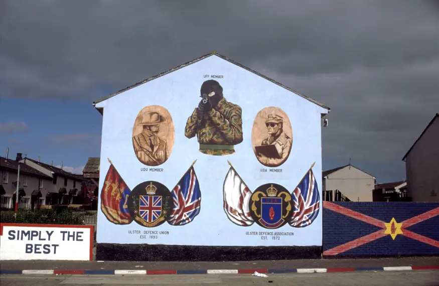 Mural in Protestant Shankill Road area of Belfast honoring the  Ulster Defence Union (UDU), Ulster Defence Association (UDA) and Ulster Freedom Fighters (UFF). 
Inscription reads, ""Simply the best / UDU Member (pictured on left top) / UFF Member (pictured on top center)  / UDA Member  (pictured on right top) / Ulster Defence Union Est. 1893 (Logo on bottom left) / Ulster Defence Association Est. 1972 (Logo on bottom right)""