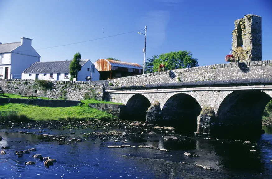 An old stone bridge crosses a stream in the small village of Doonbeg, County Clare.