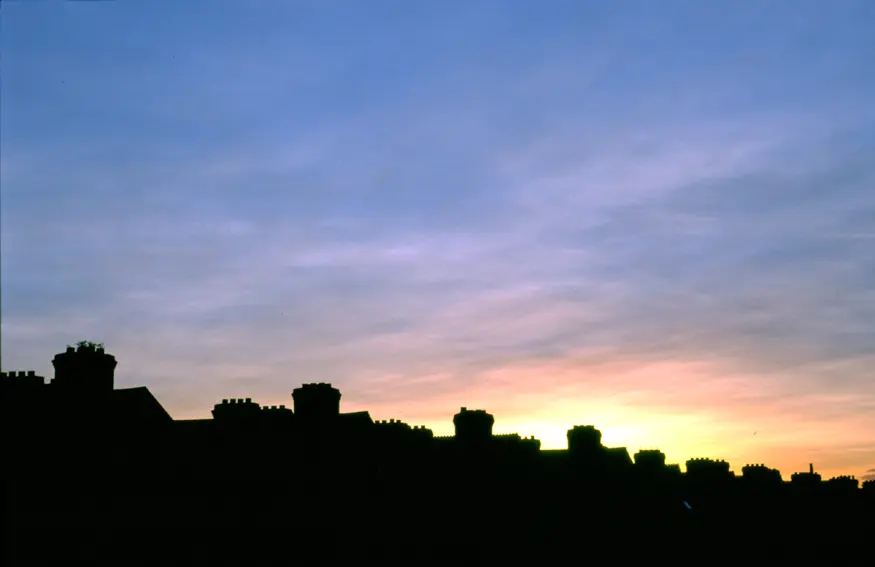 The sun sets over row houses on the streets of Dublin.