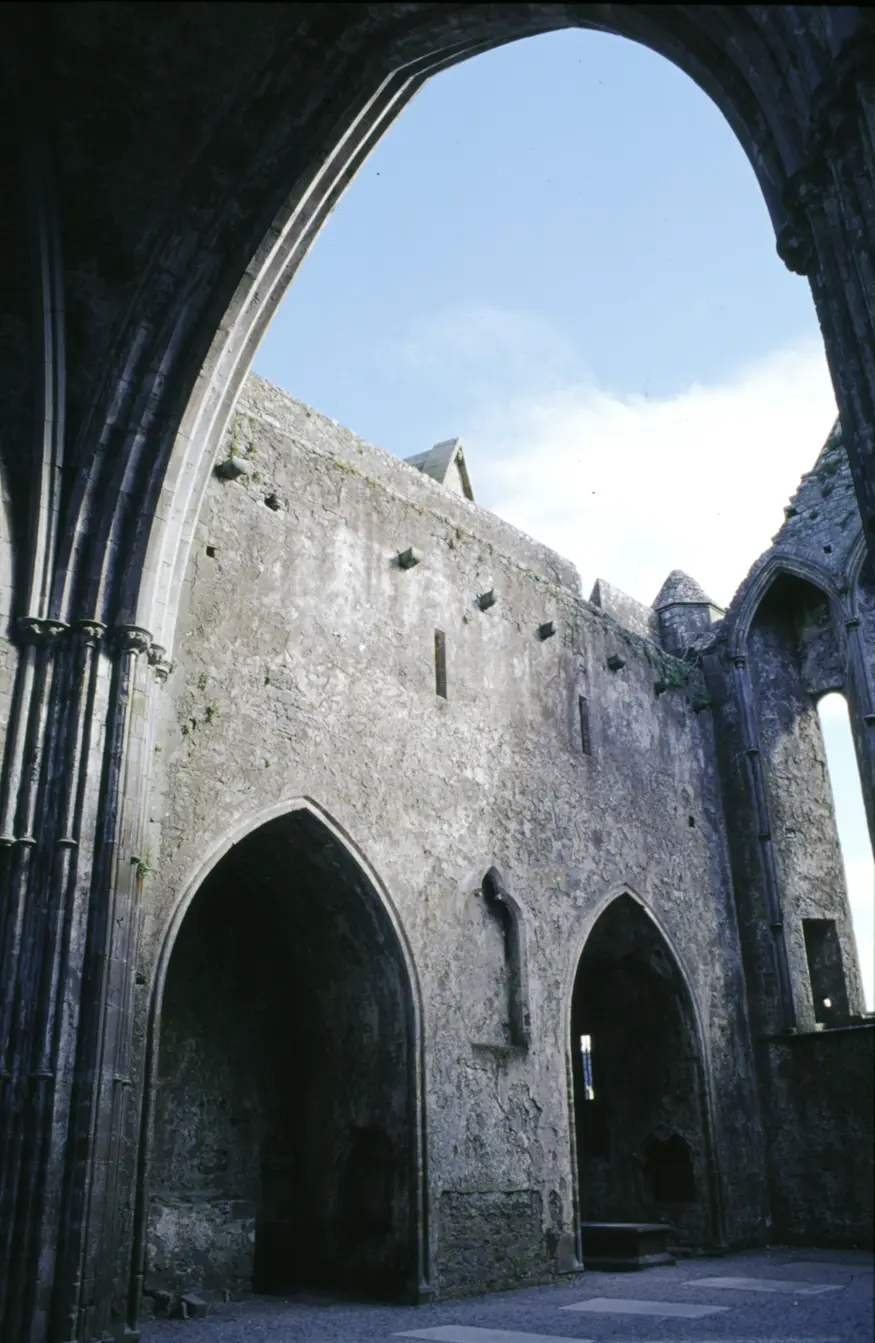 The arches of a 700 year old gothic cathedral on the Rock of Cashel. Other medieval stone buildings share the view from the Rock, rising high off the surrounding plains on this solitary hill.