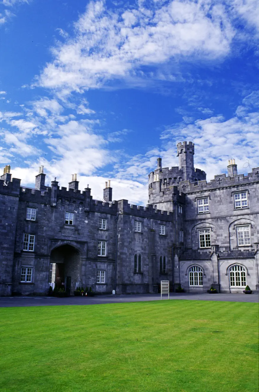Originally built in the 12th century, Kilkenny Castle is pictured here with an exceptionally green lawn and blue sky.