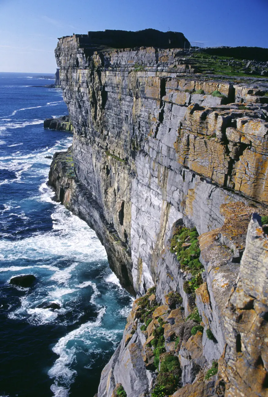 Surf crashes along an 87-meter high cliff of Inishmore Island, County Galway. The view looks out over the 3,000-year-old Dun Aengus ring fort, inhabited from 1100 BC to 1000 AD. (The fort stands on top of the cliff.)