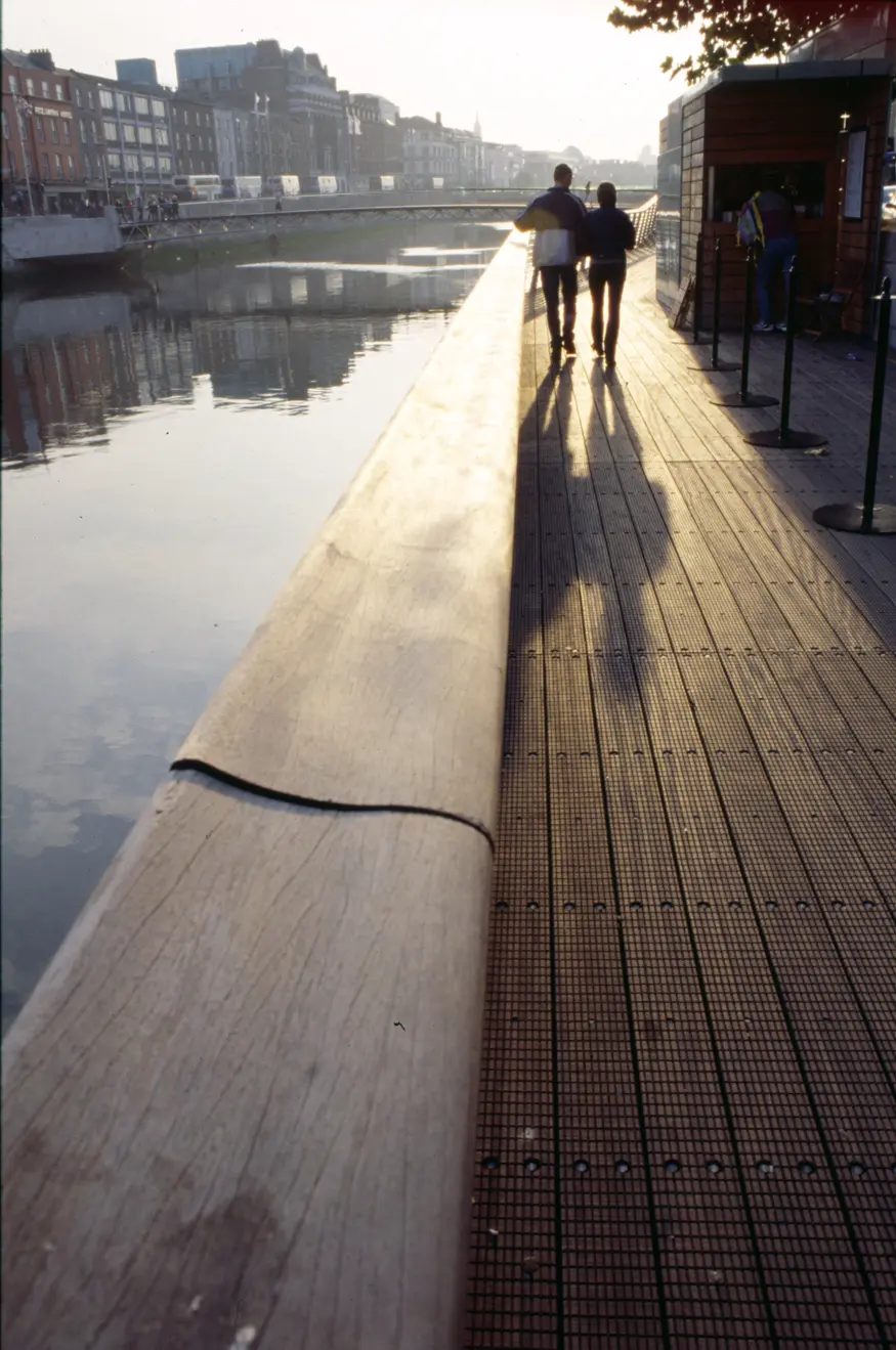 A couple walks adjacent to Dublin's famous River Liffey during sunset.