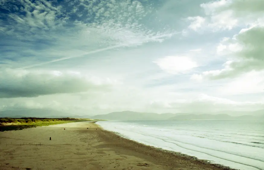 The sun shines patches of light onto a beach in the Dingle Peninsula.