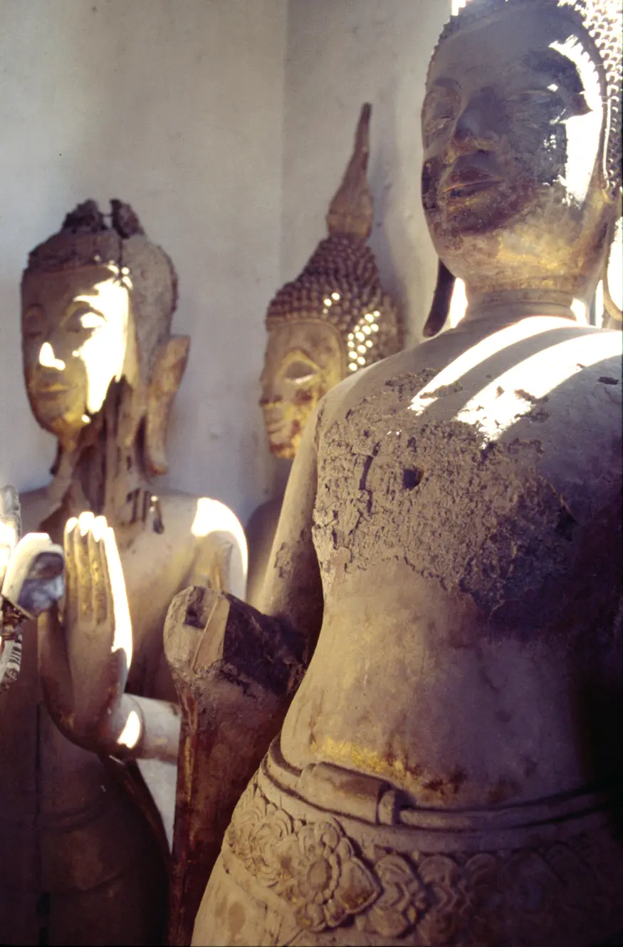 Damaged wooden carved Buddhas and other statues lie stacked in the back of Luang Prabang's Wat Xieg Thong, Laos.