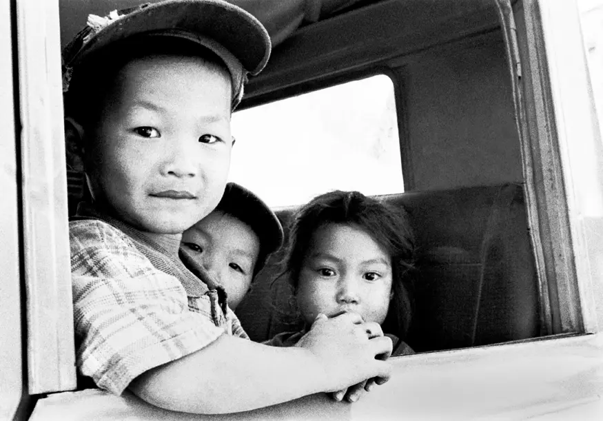Three Laotian children look curiously out the window of their parents' pickup truck in Luang Prabang, Laos.