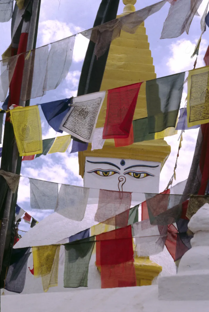 Buddha's eyes peer from behind prayer flags at a stupa near the massive Bodhnath temple.