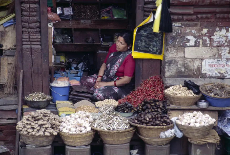 A woman sells dried chilies, garlic, ginger, and other dry goods from a booth in Kathmandu's Durbar Square.