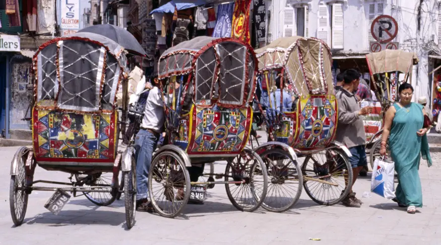 Four rickshaw drivers wait for business on a busy Kathmandu street.