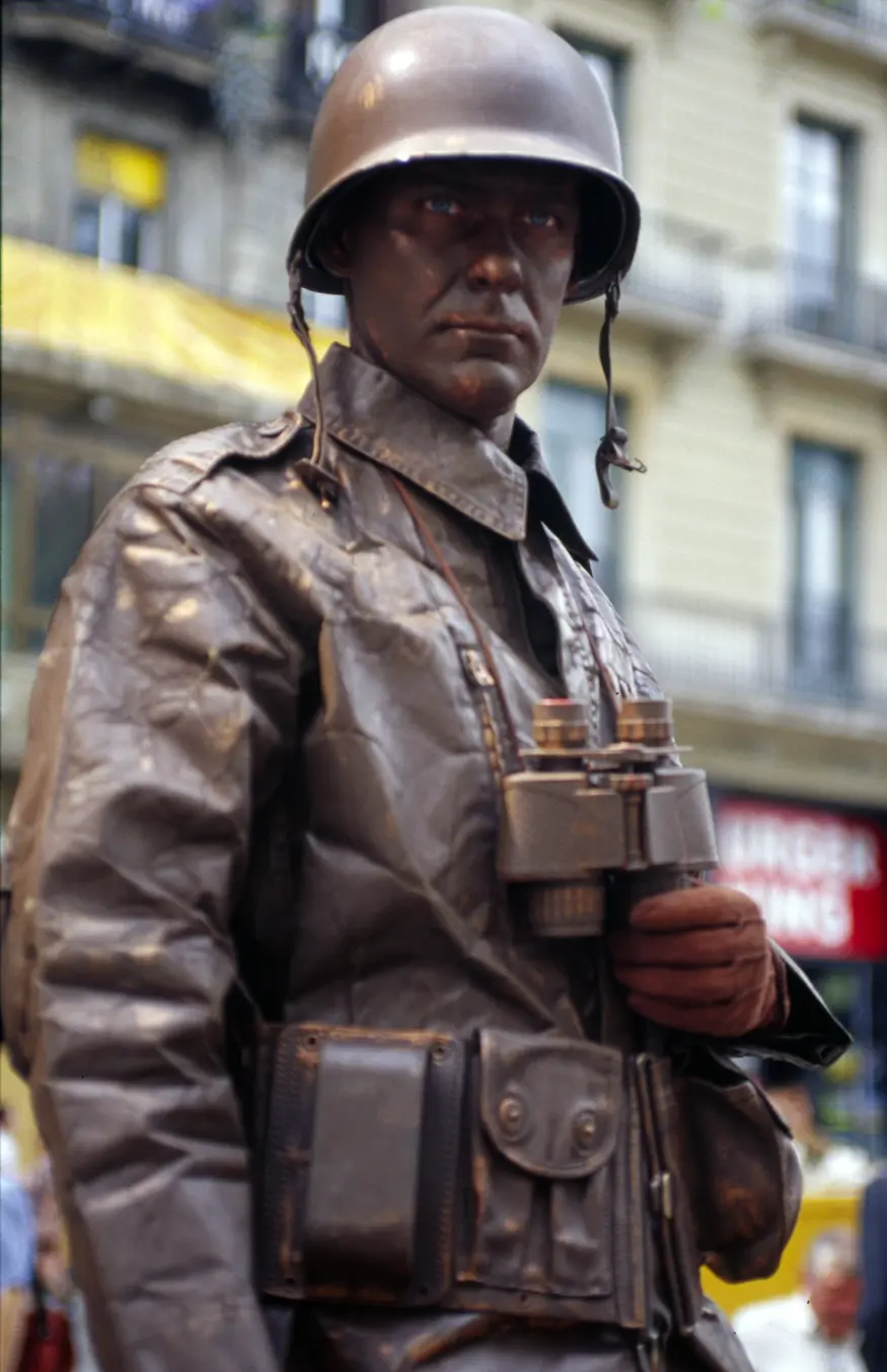The tree-lined pedestrian area of Barcelona's La Rambla attracts tourists, locals, and street performers such as this human statue. This brown soldier stands still until offered a coin, then he gives an inspiring John Wayne salute and a wink.
