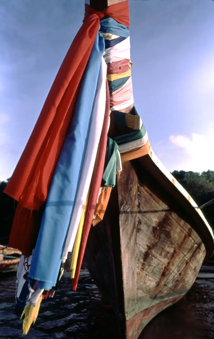 A colorful Thai sea gypsy boat is decorated with streamers that help to keep the sailors safe.